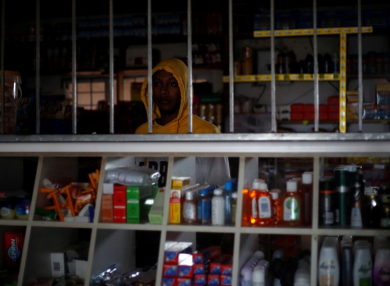 A shopkeeper serves a customer during an electricity load-shedding blackout in South Africa