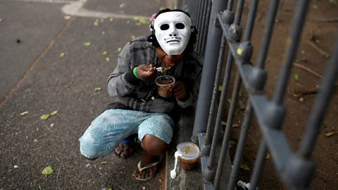 Getty Images In Rio de Janeiro, a person who is homeless eats food provided by residents of the Chapeu Mangueira slum during the Covid-19 outbreak (Credit: Getty Images)